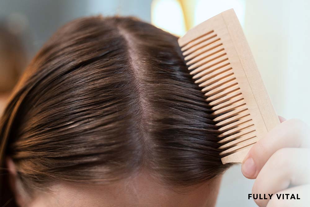 Woman brushing her hair with a wooden brush