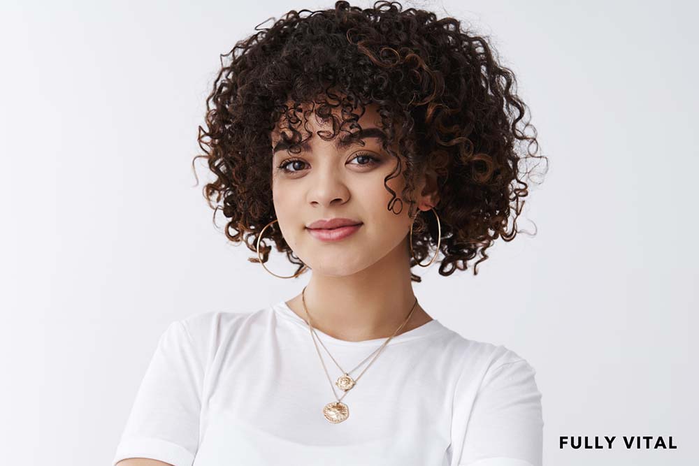 Woman in white with curly hair with bangs
